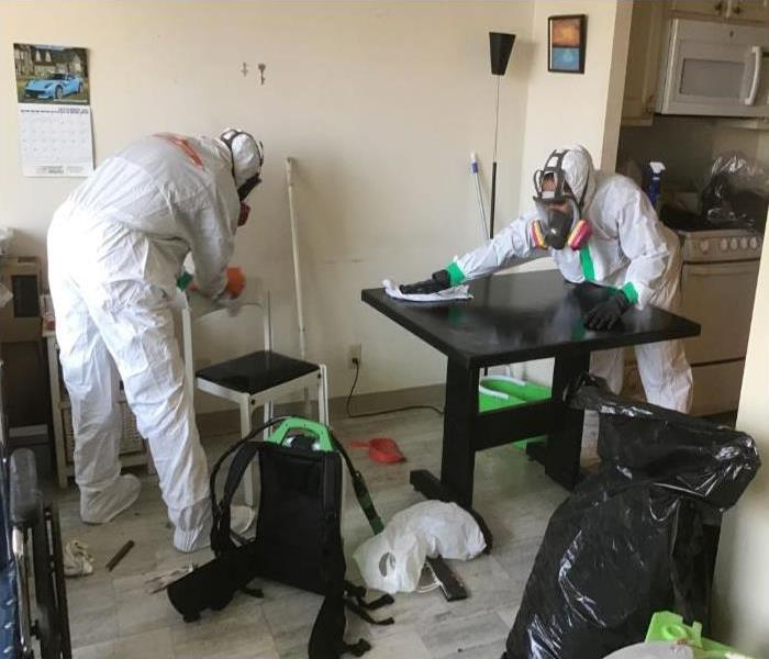technicians in protective suits disinfecting tables